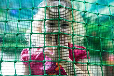 Close-up portrait of smiling girl looking through fence