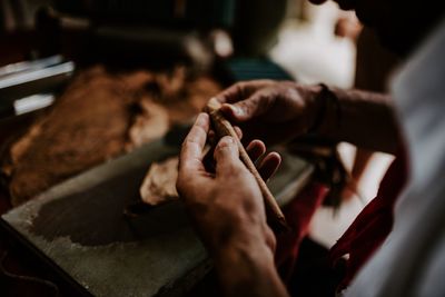 Cropped hands of craftsperson making cigar leaves at workshop