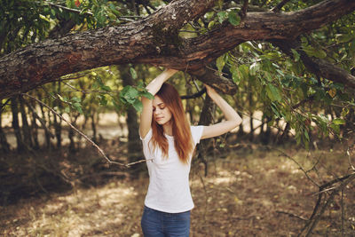 Full length of woman standing by tree