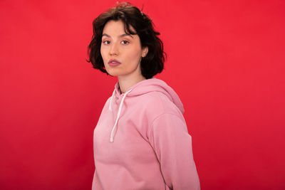 Portrait of woman standing against red background