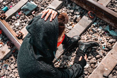 High angle view of woman sitting on railroad tracks