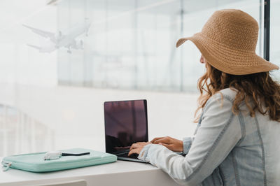 Side view of woman using mobile phone while standing in office