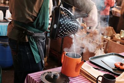 Midsection of man pouring boiling water from kettle at borough market