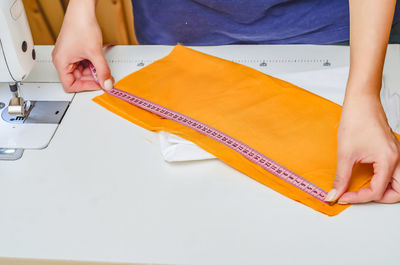 Dressmaker measures the cloth for sewing clothes with measuring tape