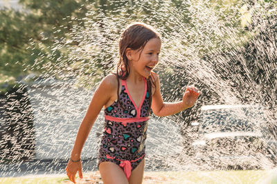 Water splashing on playful girl in yard