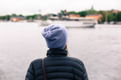 Rear view of woman standing by sea against sky