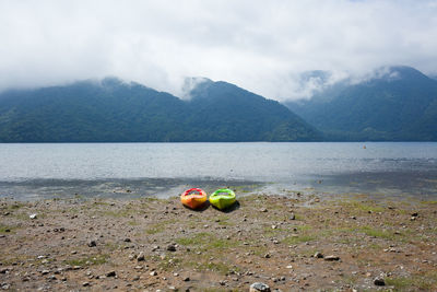 Kayaks at lakeshore against mountain