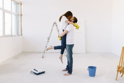 A young couple in love have moved into a new house and are making repairs painting white walls