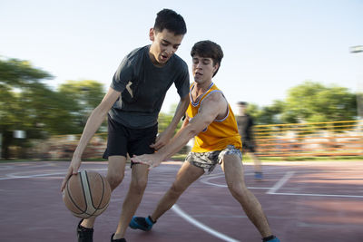 Teenage boys playing street basketball