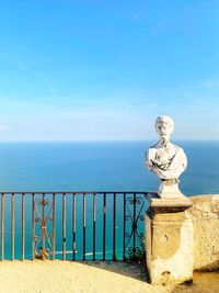 Sculpture by sea against blue sky