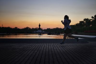Woman running at lakeshore against sky