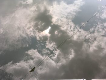 Low angle view of power lines against cloudy sky