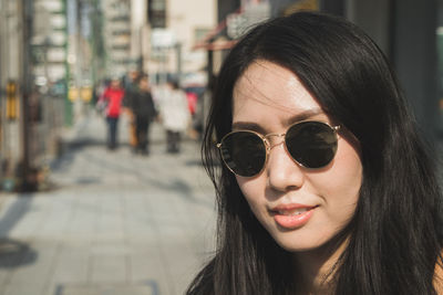 Close-up of smiling woman wearing sunglasses in city