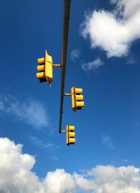 Low angle view of yellow sign against sky