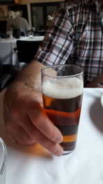 Close-up of hand holding beer glass on table