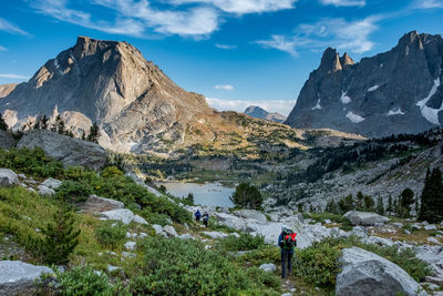 Woman walking on field against rocky mountains