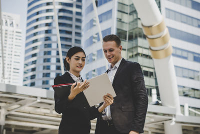 Low angle view of business people discussing while standing against building