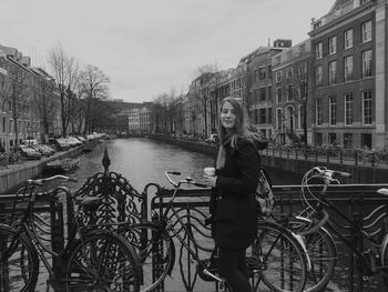 Woman standing by bicycle in city