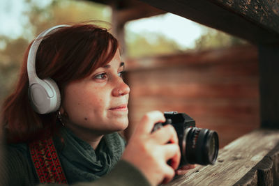 Young woman taking photos in a wooden hide with an old analog camera