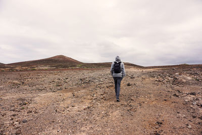 Rear view of man standing on mountain against sky