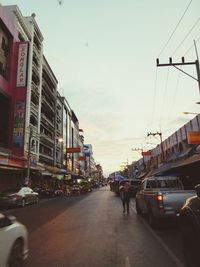 Vehicles on road against sky in city