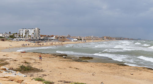 Buildings by sea against sky in city