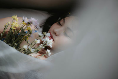 High angle view of woman holding bouquet while sleeping on bed at home