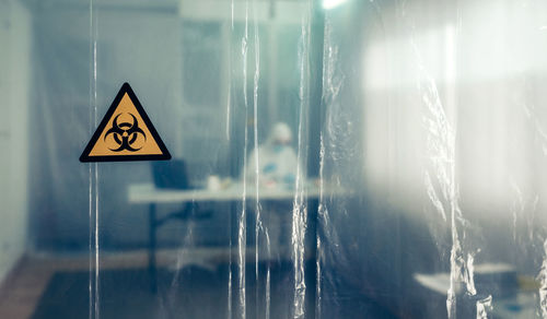 Scientist working in hospital seen through plastic curtain