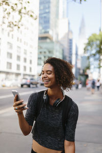 Woman with headphones using smart phone in city