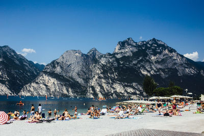 People at lakeshore against blue sky