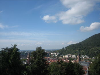 Trees in city against cloudy sky