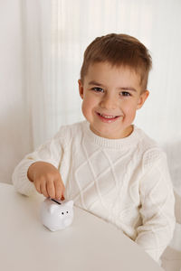 Little boy putting money coin into piggy bank for saving money. wealth, budget, investment