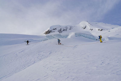 Rear view of hikers at snowcapped mountain against sky