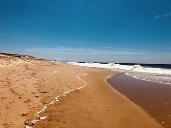 Scenic view of beach against blue sky