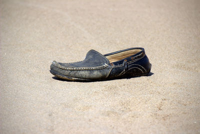 Close-up of shoe on sandy beach
