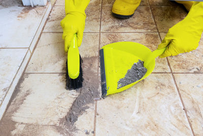 Person wearing gloves cleaning dust with duster at home