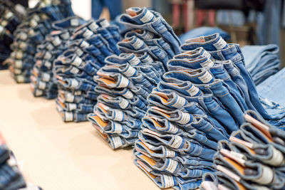 Blue denim jeans stack on wooden table on top in clothing store, modern shopping mall. folded jeans