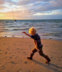 Blonde-haired boy striding into the wind at the beach