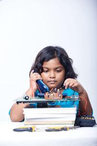 Portrait of young woman using mobile phone against white background