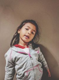 Portrait of a smiling girl standing against wall