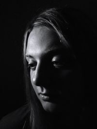 Close-up of thoughtful young woman against black background