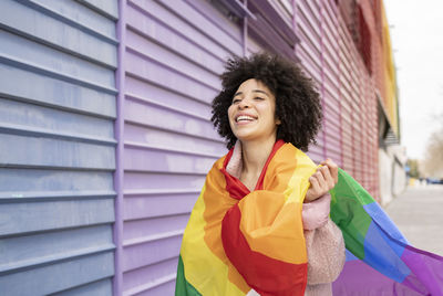 Cheerful woman wrapped in rainbow flag