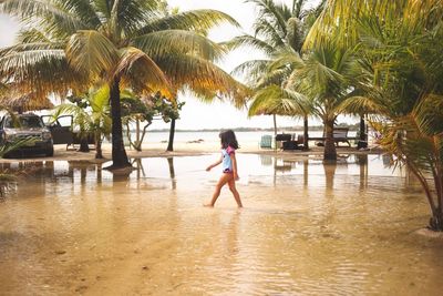 Woman walking by swimming pool against sky