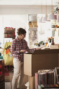 Owner unpacking box while listening music at store