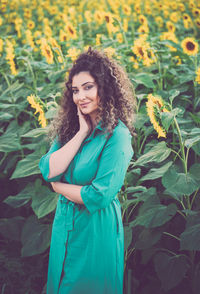 Portrait of smiling young woman standing against sunflowers