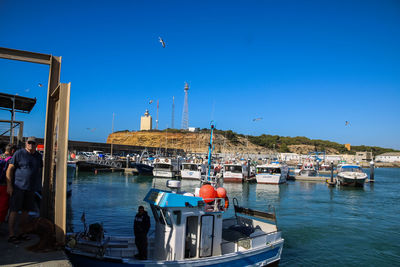 Sailboats moored on sea against clear blue sky