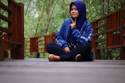 Young woman looking away while sitting on wood