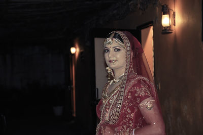 Portrait of woman standing against illuminated wall