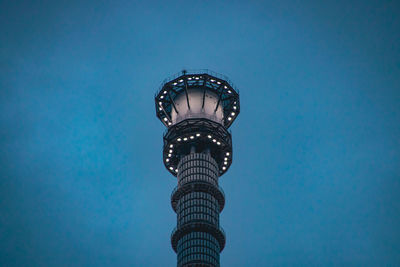 Low angle view of illuminated tower against blue sky