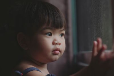 Close-up of cute girl looking through window